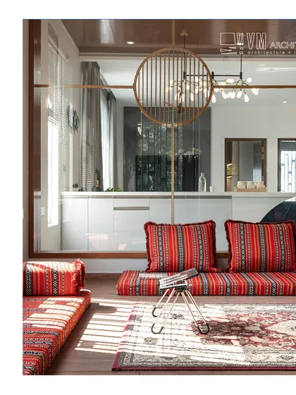 A traditional floor seating ('diwan') area in Sa Sha Villa, featuring vibrant red patterned cushions that add a splash of color and cultural richness to the modern space.