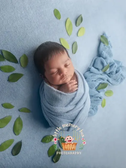 A creative take on the wrapped newborn pose, with green leaves arranged to look like butterfly wings. It's a sweet and artistic way to capture your little one.