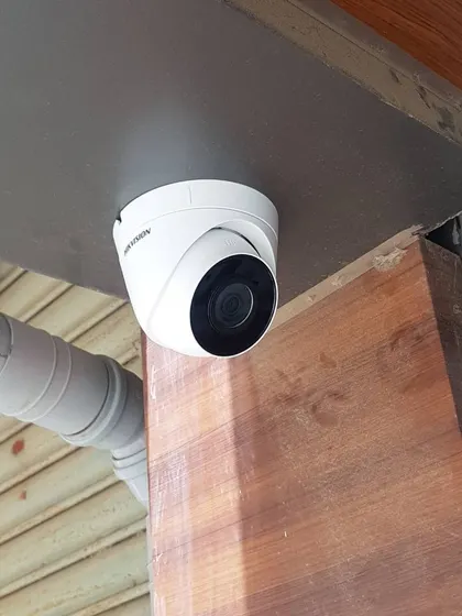 A Hikvision dome camera installed under an overhang. This type of camera is less obtrusive and provides a wide field of view for areas like patios and entryways.