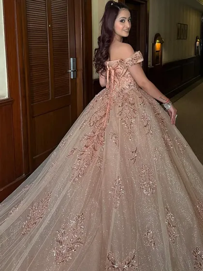 The perfect princess pose in our rose gold ball gown. This shot from the back shows the corset lacing and the way the voluminous, embroidered trail drapes beautifully.