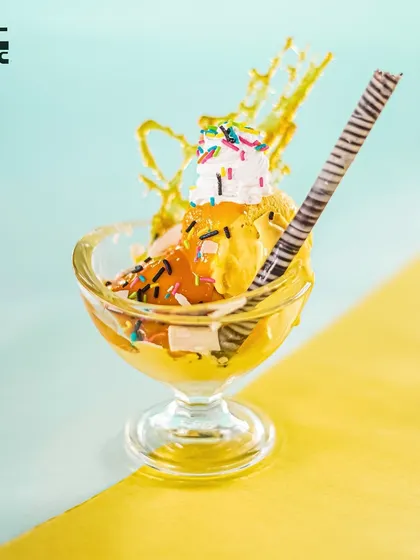 Our Banana Split Sundae is a delightful treat, topped with sprinkles, chocolate chips, and a wafer stick.