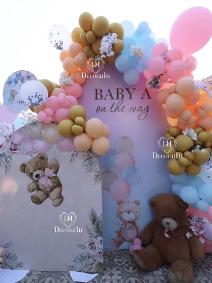 A teddy bear-themed baby shower setup with a pastel balloon arch and custom backdrops.