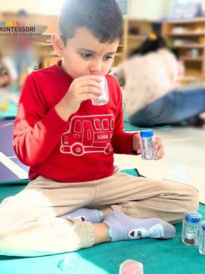 A child engages with smelling jars, a classic sensorial activity that refines the olfactory sense and helps children classify and describe different scents.
