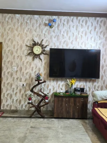 A living room TV wall with a subtle feather or leaf pattern wallpaper.