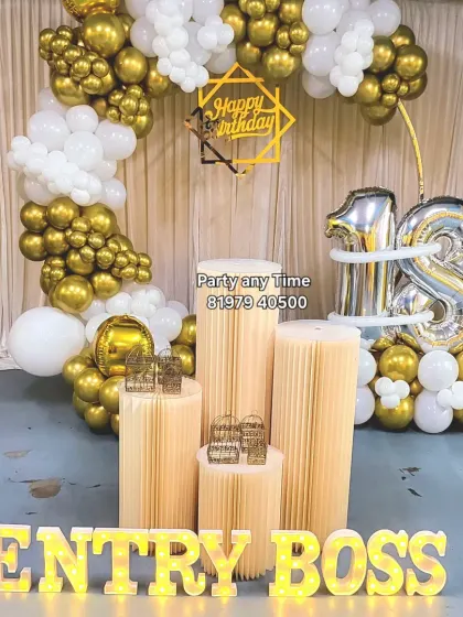A stylish 18th birthday setup with a white and gold balloon arch and light-up letters spelling "ENTRY BOSS".