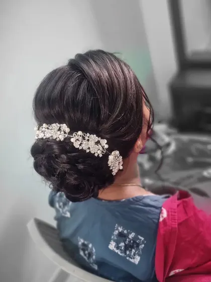 A classic and elegant bridal bun. This intricate updo is decorated with a beautiful crystal hair accessory, perfect for a reception or engagement party.