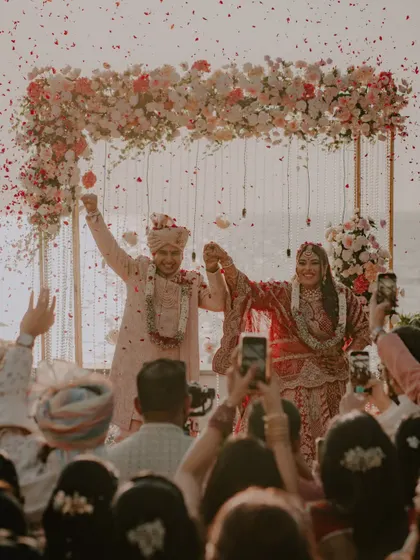The couple celebrates their union under a shower of flowers after their beachside ceremony. This is a moment of pure triumph and happiness.