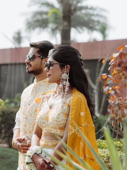 A stylish portrait of the couple in their Haldi attire, wearing sunglasses and striking a cool pose together.
