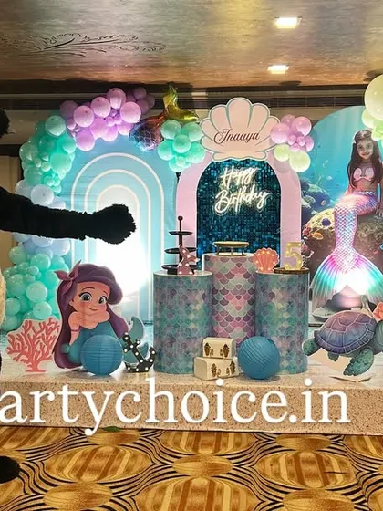 An underwater fantasy with our mermaid theme, complete with a friendly panda mascot. This stage decoration includes a pastel balloon arch, character cutouts of Ariel and a sea turtle, and themed pedestals on a raised platform.