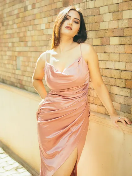 A full-body shot against the brick wall, highlighting the outfit and pose. The harsh light creates interesting shadows, adding depth and texture to this urban fashion portrait.