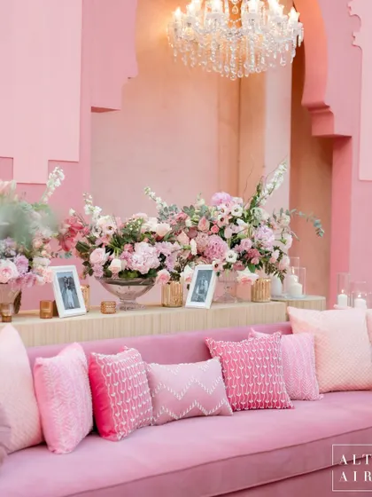 A cozy lounge sofa at the 'Echoes of Pink' wedding, adorned with pillows in various shades and textures of pink. Every detail was curated to create a harmonious and romantic setting.