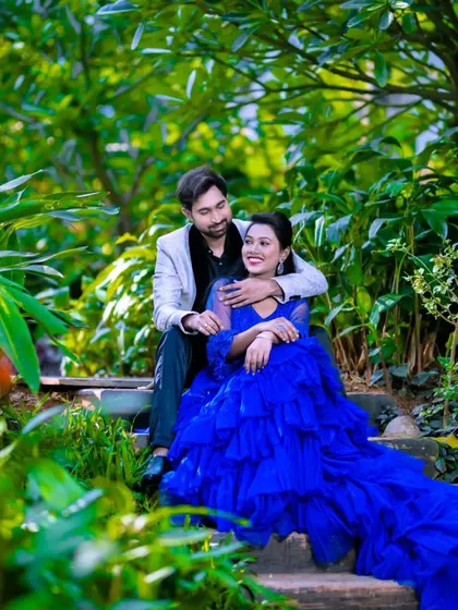 A sweet moment in a lush garden. The royal blue of her ruffle gown creates a beautiful contrast with the greenery, while his suit adds a touch of formal elegance.