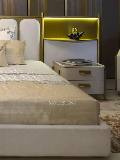 Another angle of the Solitaire bed, showing how it pairs with a matching bedside table and a cozy armchair to create a complete, luxurious bedroom setting. The design is a perfect blend of comfort and aesthetics.