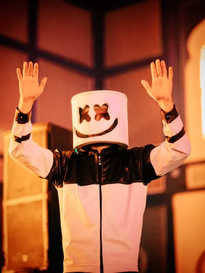 An entertainer dressed as the DJ Marshmello gets the crowd hyped, adding to the high-energy, festival-like atmosphere of the after-party.