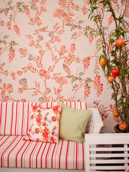 A lounge sofa set against a wall with custom pomegranate-themed wallpaper, showing how we carry a theme through every element.