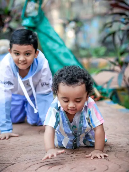 Two young brothers are captured crawling and playing on a stone path in a park. This candid shot is full of life and perfectly captures the energy and fun of childhood.