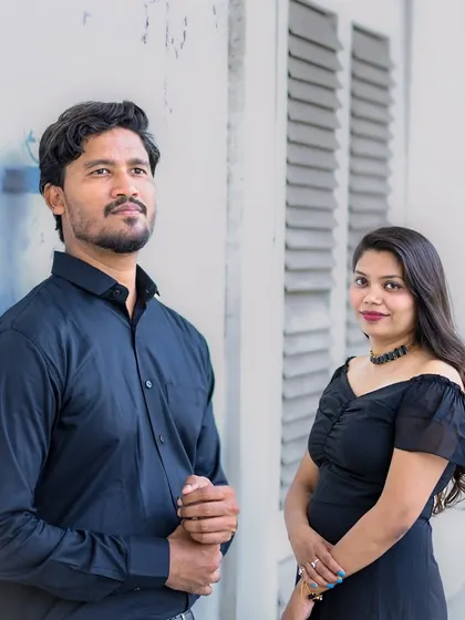 A stylish portrait of the couple posing individually but together in the frame, set against a white textured wall with vintage shutters.