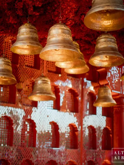 A detail shot of the handcrafted temple bells hanging within the 'Kaanch Bagh' mandap. These elements added a kinetic and auditory layer to the sacred space, enhancing the traditional feel.