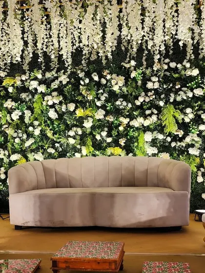 The centerpiece of the Green Vidhi stage, featuring a comfortable sofa for the couple, framed by a wall of white flowers and hanging wisteria.