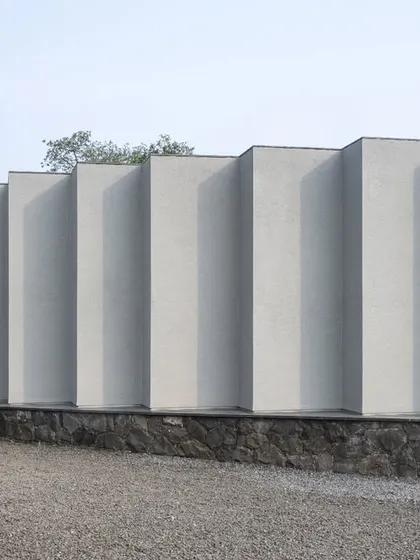The exterior wall of the Vismaya museum is articulated with a series of deep, vertical fins. This creates a rhythmic facade that changes in appearance with the movement of the sun, playing with light and shadow throughout the day.