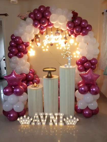 An elegant arch decoration in magenta and white for a home birthday party. I used hanging lanterns and fairy lights within the arch to create a warm and inviting glow.