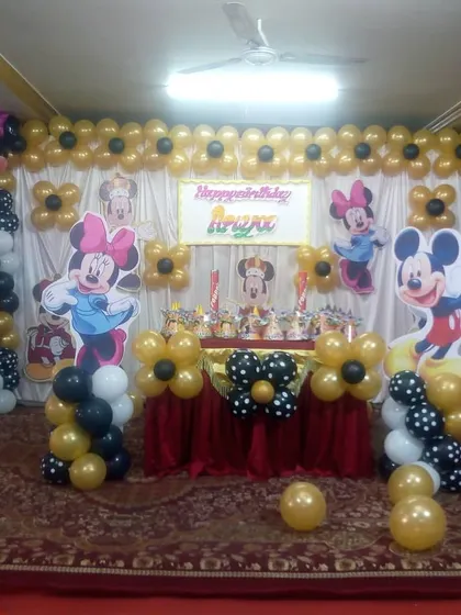 A classic Mickey and Minnie Mouse birthday party theme for Apoorv. The decoration uses a black, gold, and white color scheme with character cutouts and flower-shaped balloon arrangements.