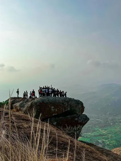 A team stands triumphantly on a massive rock overlooking the valley at Bananthimari, a perfect 'king of the world' moment.