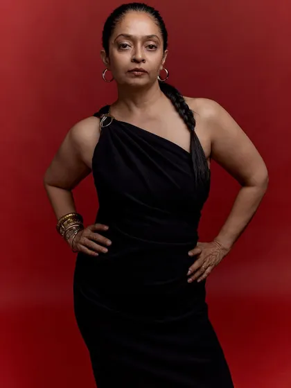 A powerful stance celebrating a 50th birthday. The combination of the strong pose, elegant black dress, and bold red background creates a portrait of pure confidence.