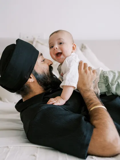 A father playing with his baby on the bed. The joy and laughter between them are heartwarming.