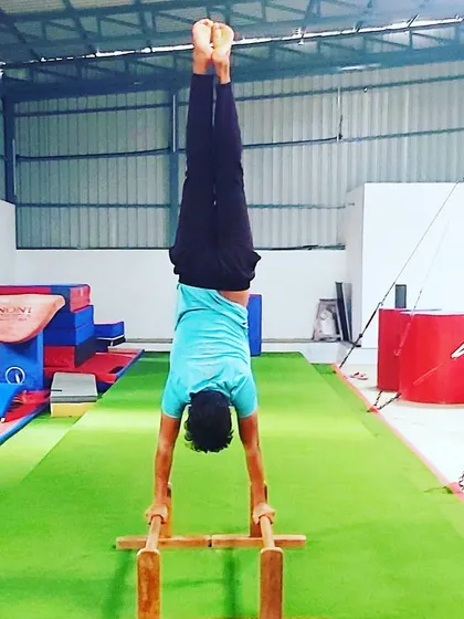 A clean handstand on the parallettes, demonstrating excellent balance and shoulder strength. This is a result of consistent conditioning and practice.