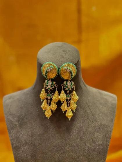 Jewelry that turns heads. These green and gold jhumkas feature a beautiful stud with delicate tassels, adding graceful movement with every turn.