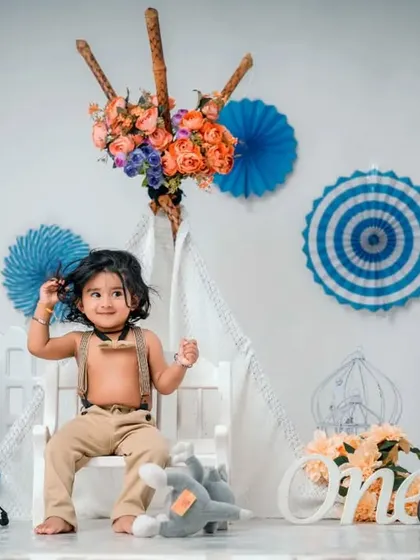 A classic first birthday studio setup. This portrait captures a happy baby in a teepee setting with 'ONE' blocks and festive decorations.