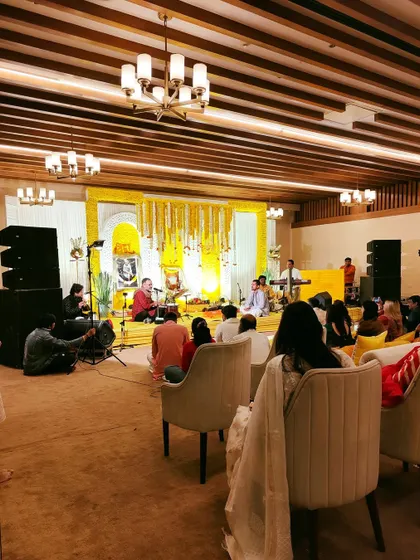 The indoor setup for the Sai Sandhya, where guests are seated facing the stage decorated with marigolds, ready for an evening of devotional music and blessings.