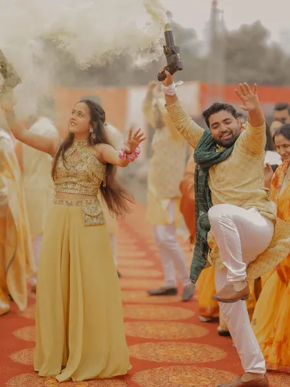 The couple makes a grand, fun-filled entrance at their Haldi ceremony, dancing with color smoke guns.