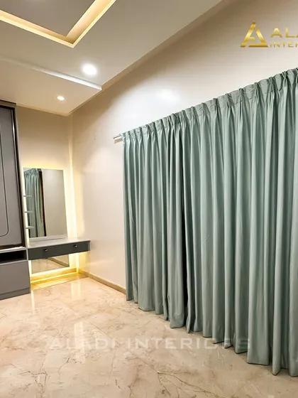 A view of the dressing corner in a bedroom, showing the wardrobe and vanity table, with elegant mint-green curtains adding a touch of softness.