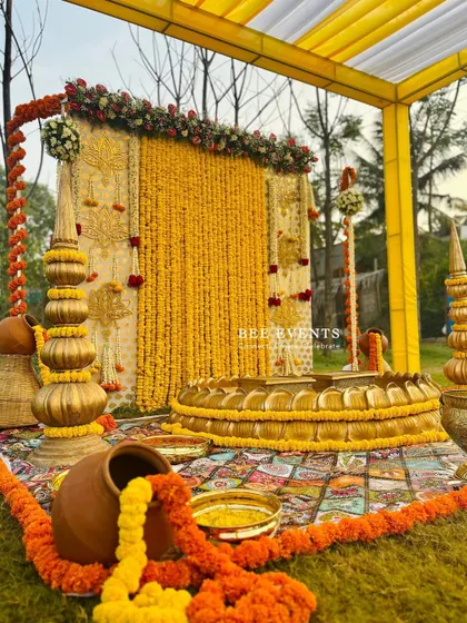 A beautiful shot of our outdoor Haldi setup, ready for the ceremony. The combination of the marigold backdrop, the lotus 'urli', and the traditional props creates a scene of pure bliss.