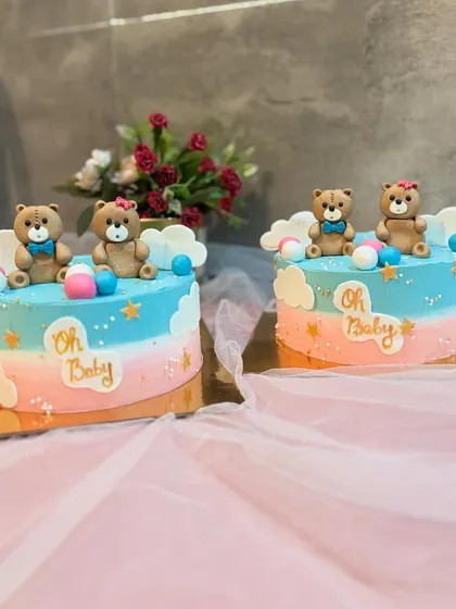 Twin "Oh Baby" cakes for a special baby shower. Both cakes feature a pink and blue ombre design and are topped with cute, matching teddy bears.