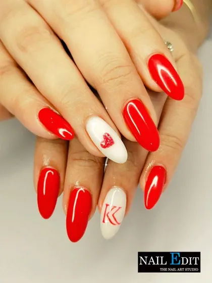 A classic Valentine's set with bold red almond-shaped nails. The accent nails feature a delicate heart and a custom initial, making it a personalized and romantic choice.