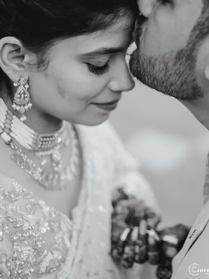 A tender black and white close-up, focusing on the groom's kiss on the bride's forehead. This style emphasizes raw emotion.