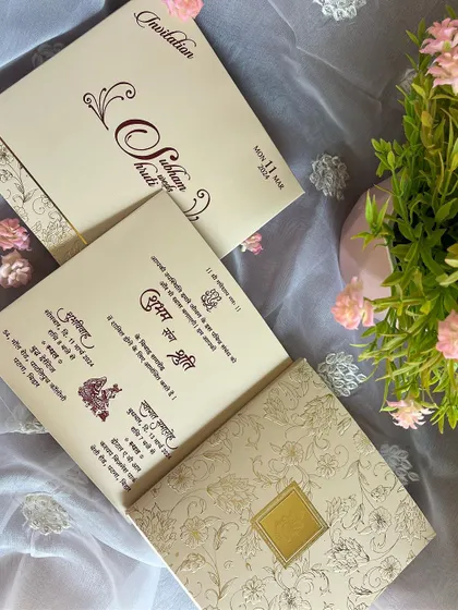 A classic invitation with wedding details printed in clear and elegant Hindi script, set within a beautiful floral-embossed folder.
