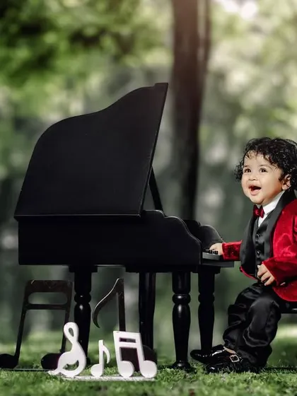 The world through the eyes of a child is pure magic. A boy in a red velvet jacket laughs with joy at his piano.