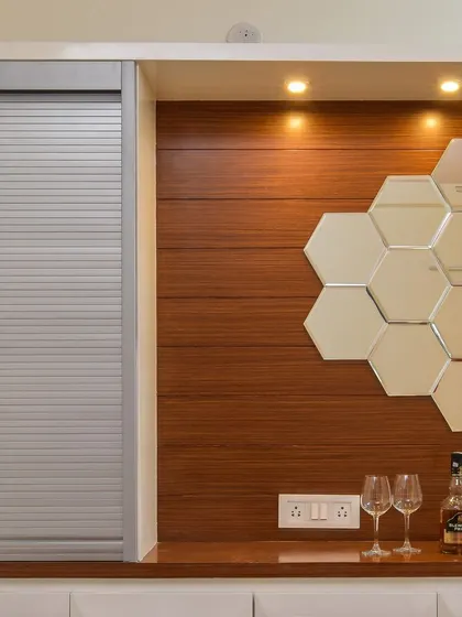A close-up of the crockery unit's bar section, which includes a roller shutter to conceal the storage area. The hexagonal mirror backsplash adds a touch of modern glamour.