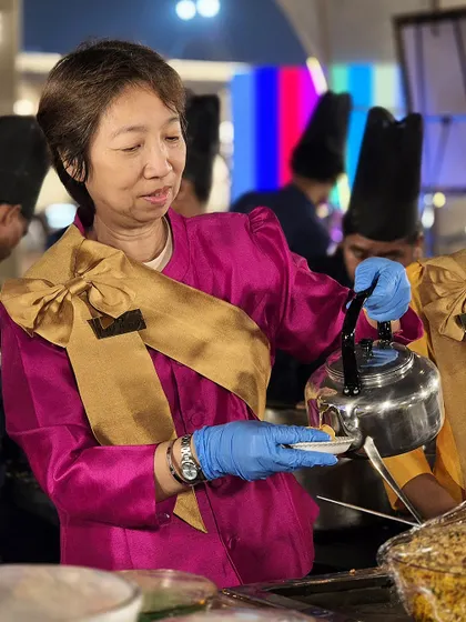A member of our international culinary team carefully prepares a dish. Her traditional attire and focused expression highlight the authenticity and expertise we bring to our Thai food station.