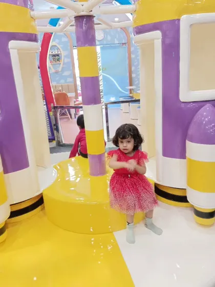 A little girl enjoys our rocket-themed merry-go-round during a school picnic. This ride is a gentle and fun attraction for our younger visitors.