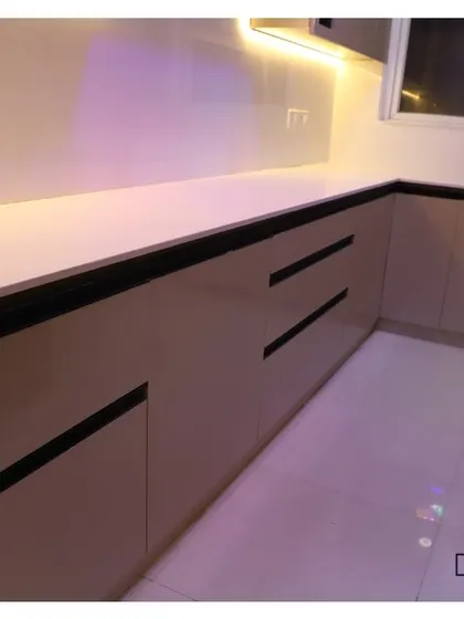 A simple and clean kitchen cabinet design, featuring beige handleless drawers and doors with black trim for a modern, minimalist look.