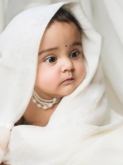 A duplicate of image 185, a close-up portrait of a baby wrapped in a white cloth, looking on with wide, curious eyes.