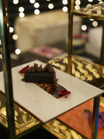 A study in chocolate. This decadent dessert is displayed on a multi-tiered golden stand, its rich layers and artistic presentation promising a truly luxurious experience.