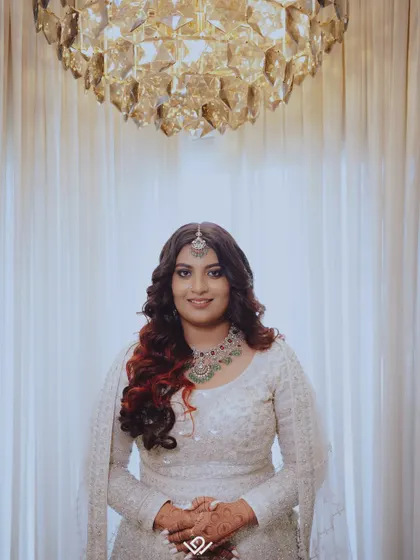 A stunning portrait of a bride with vibrant red highlights in her hair, wearing a modern silver-grey lehenga.
