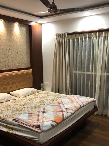 This cozy bedroom design uses a textured wallpaper accent wall behind the bed to add warmth and character. The dark wood bed frame with a simple upholstered headboard is complemented by spotlights that highlight the wall's texture.