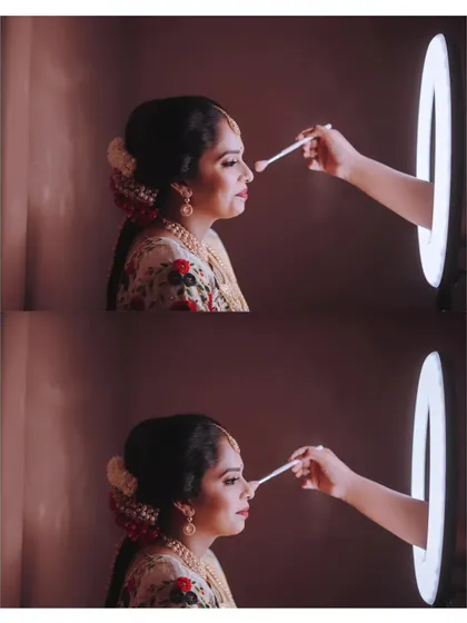 A fun and creative getting-ready shot, with the makeup artist's hand coming through a ring light to touch up the bride's makeup.